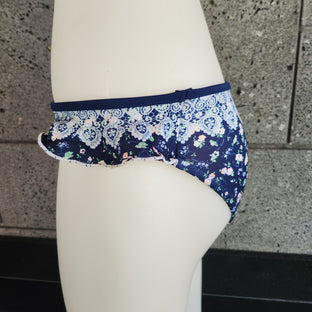 Navy floral bikini bottom on a mannequin against a stone wall background