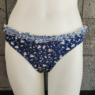 Floral-patterned bikini bottom on a mannequin against a tiled wall.