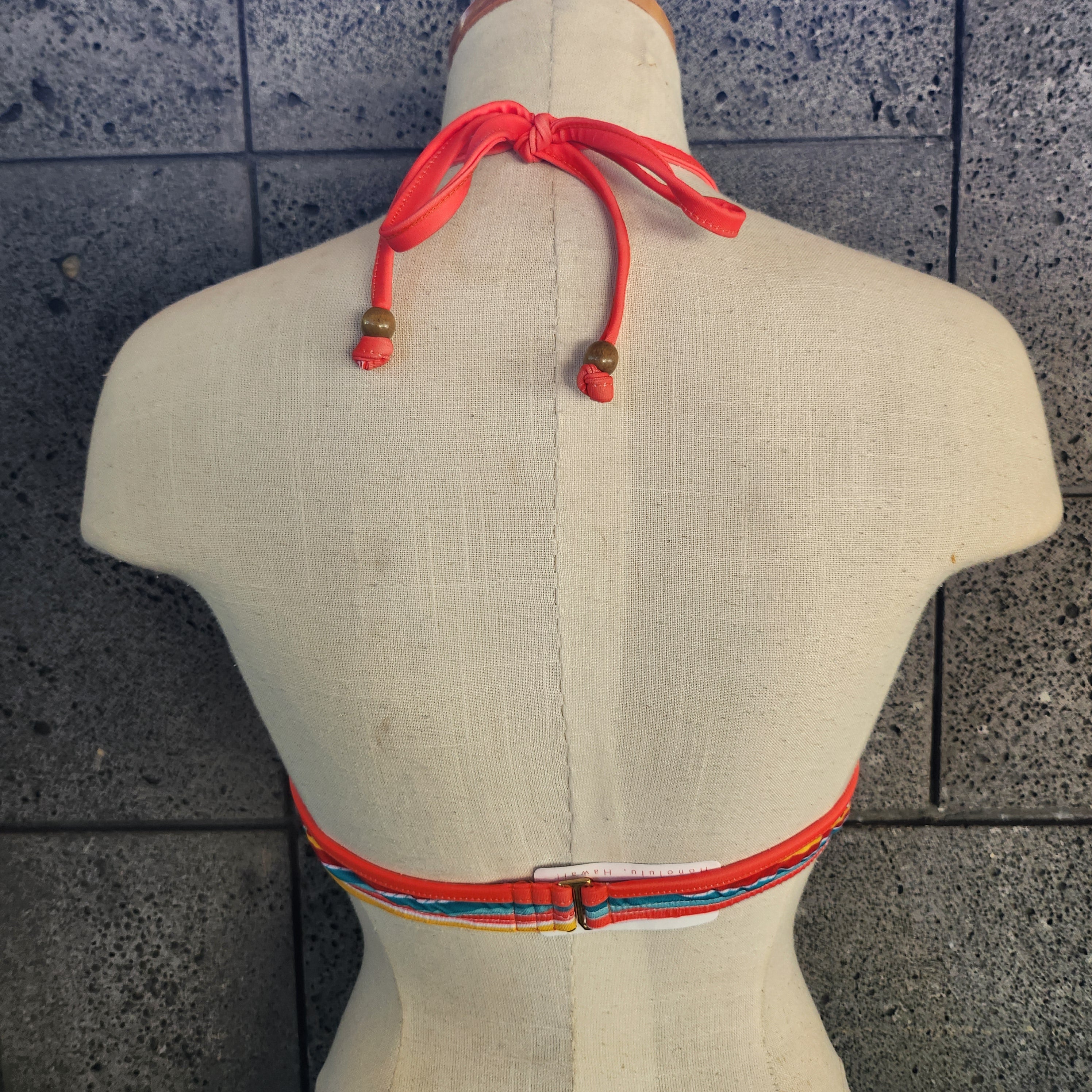 Colorful bikini top on a mannequin against a tiled wall background