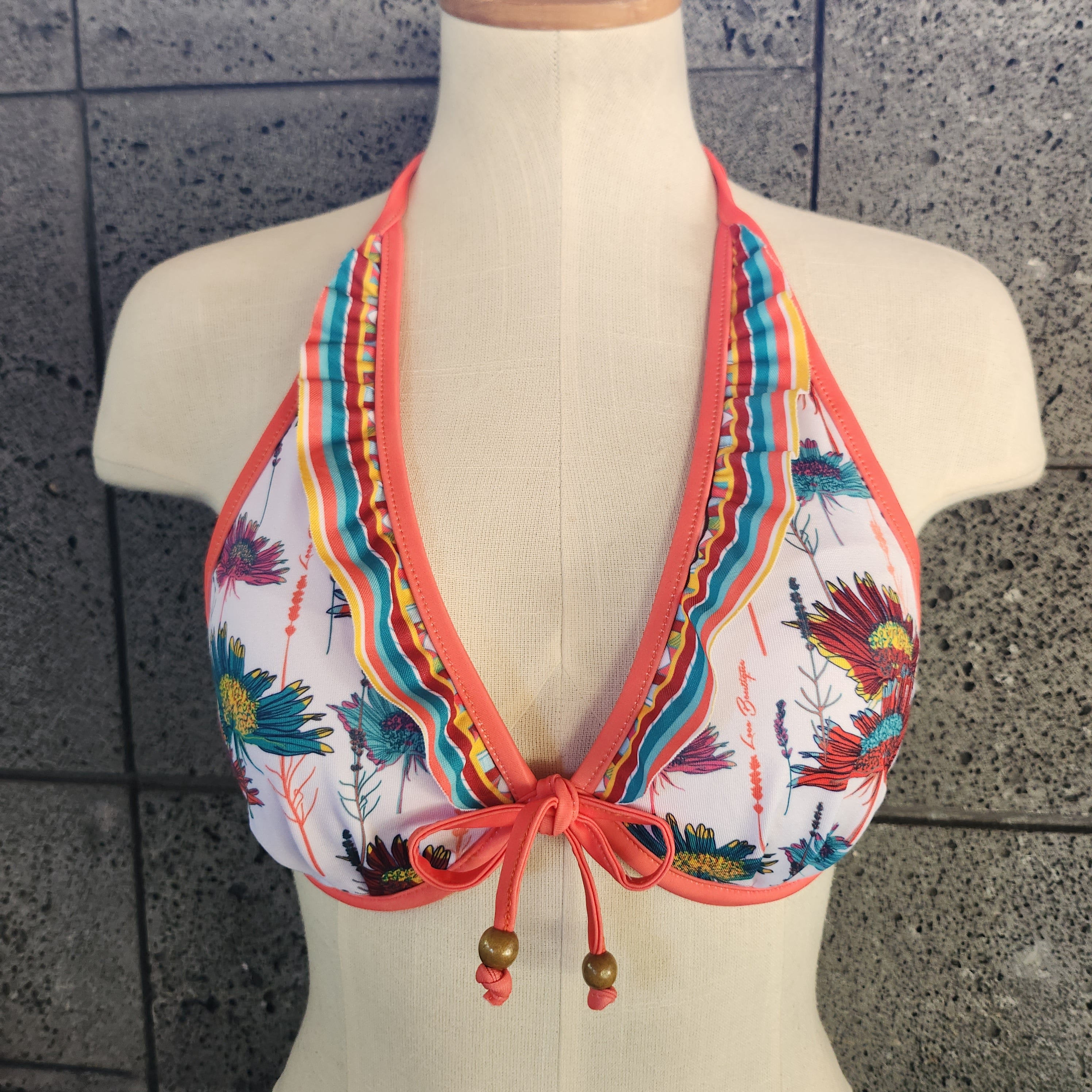 Colorful bikini top on a mannequin against a tiled wall background