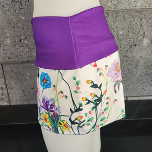 Floral-patterned skirt with purple waistband on a mannequin against a gray concrete background.