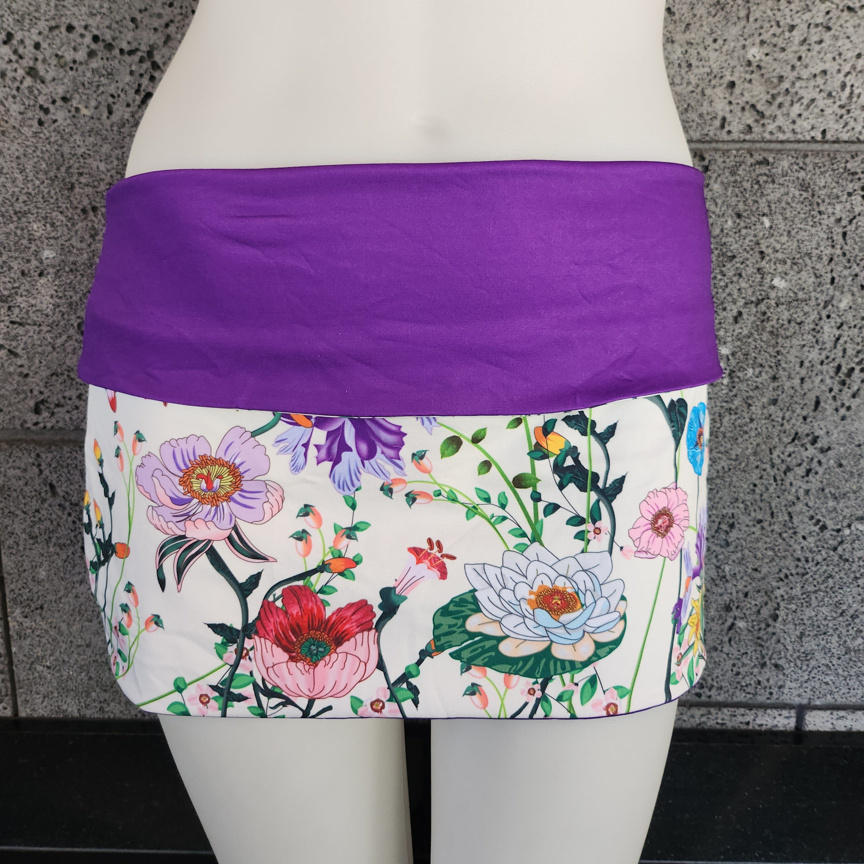 Floral-patterned skirt with purple waistband on a mannequin against a gray concrete background.