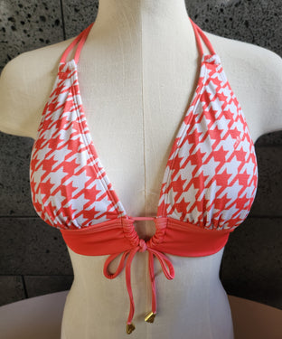 Orange and white houndstooth patterned bikini on a mannequin against a dark background