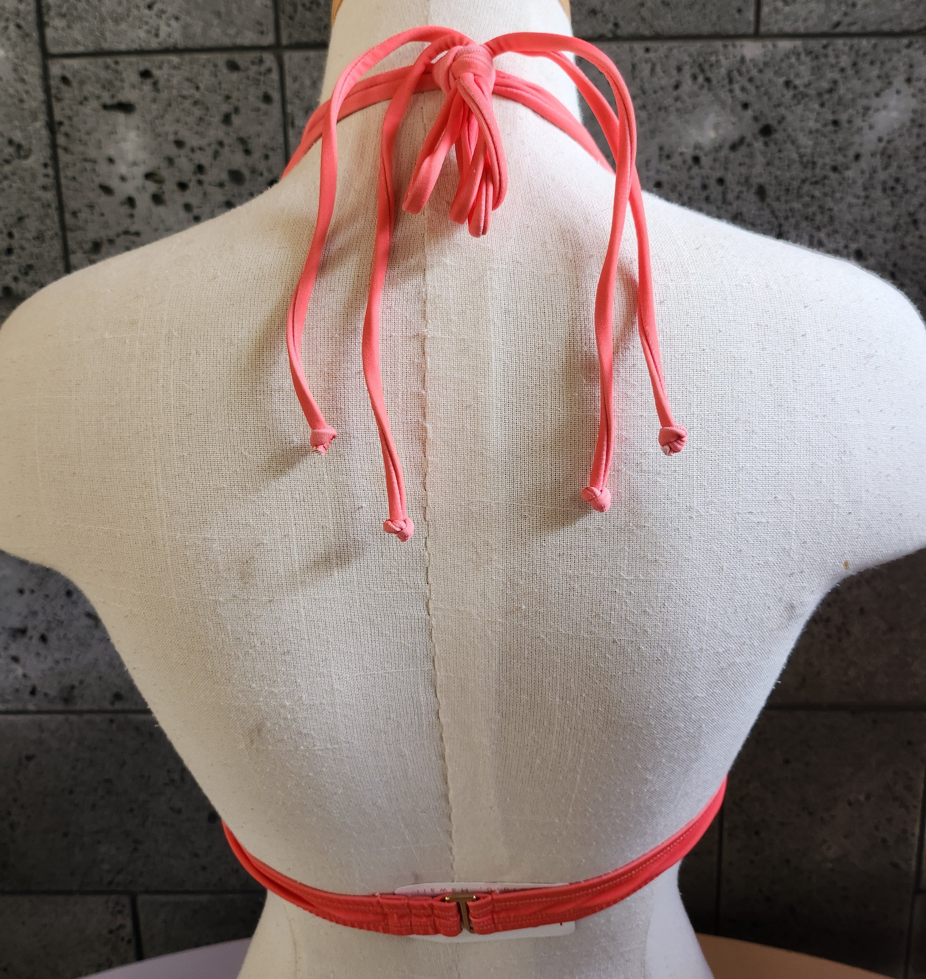 Orange and white houndstooth patterned bikini on a mannequin against a dark background