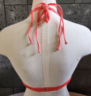 Orange and white houndstooth patterned bikini on a mannequin against a dark background