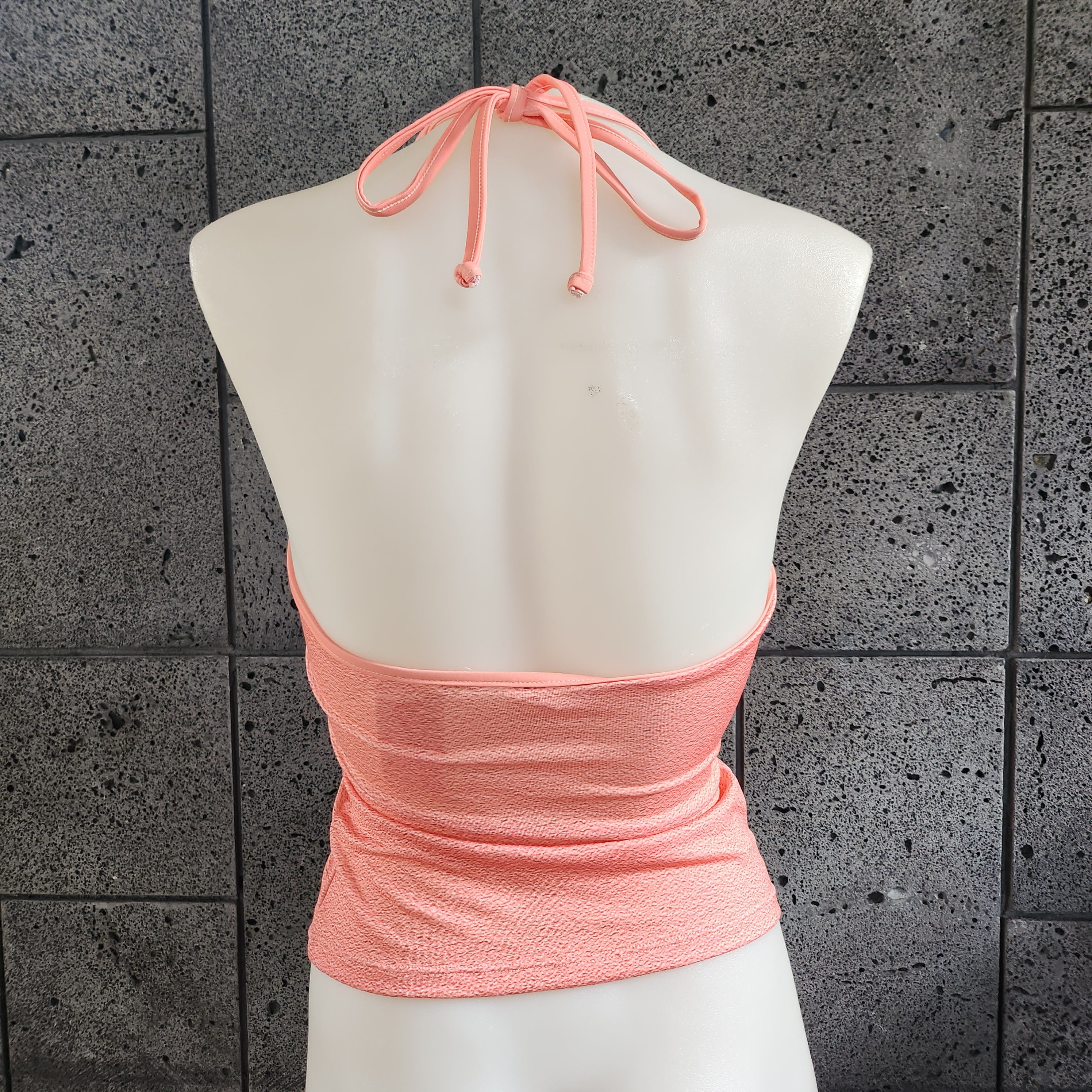 Mannequin wearing a halter tankini with palm tree design against a textured gray surface.