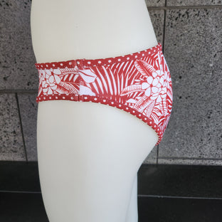 Red and white patterned bikini bottom on a mannequin against a tiled wall.