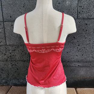 Red tankini top with embroidery details on a mannequin against a textured wall.