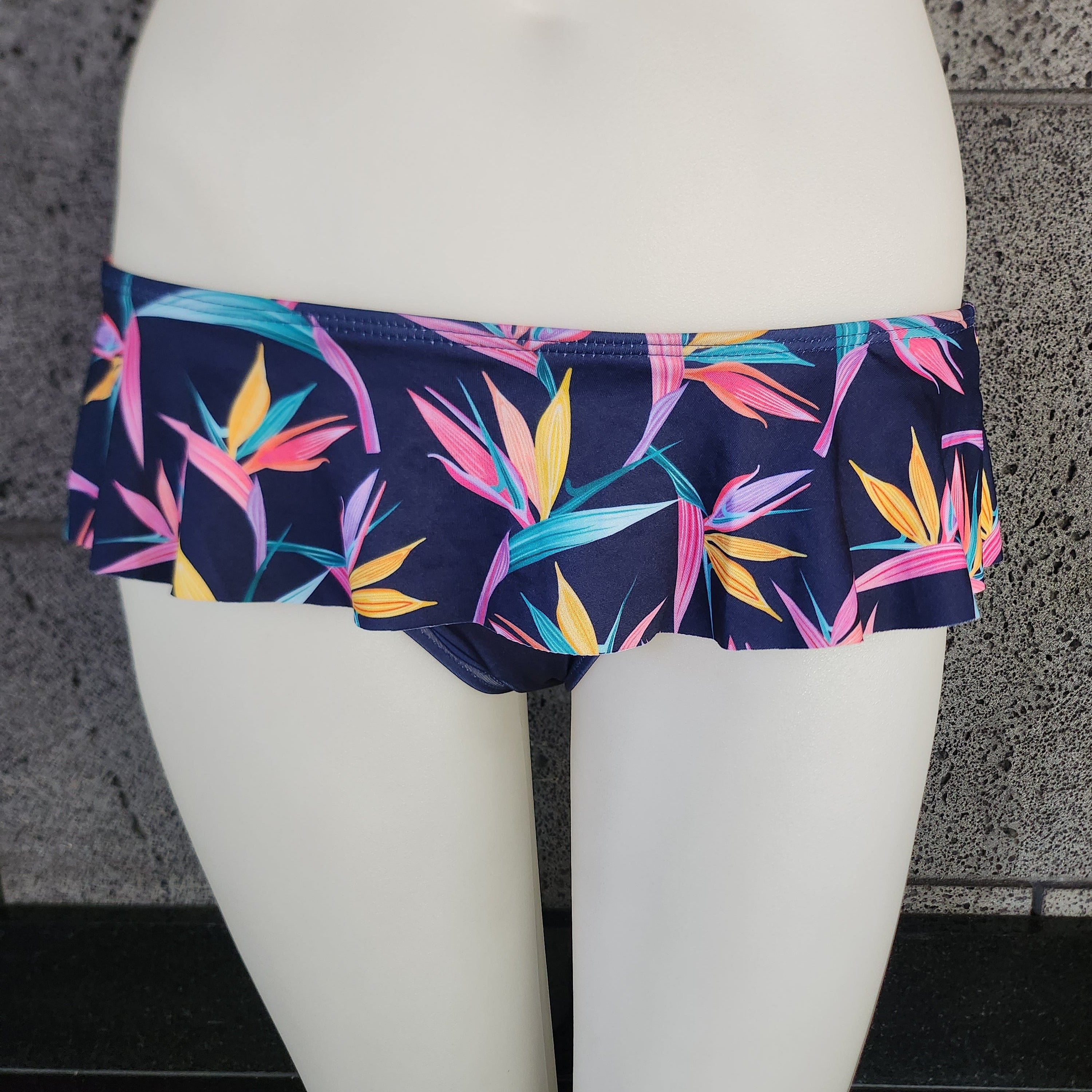 Colorful tropical leaf patterned skirted swim bottom on a model against a white background