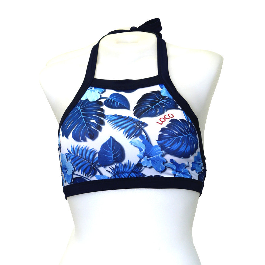 A woman wearing a blue and white floral high halter crop top with a coordinating bottom, standing against a white background.
