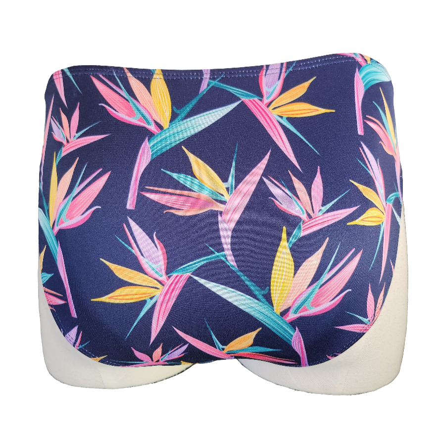 Navy blue swim bottom with colorful leaf pattern on a mannequin against a gray concrete wall.