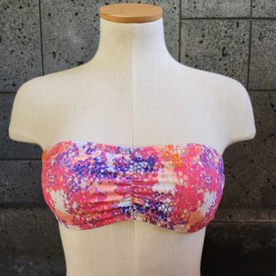 Colorful swimsuit on a mannequin against a dark tiled wall.