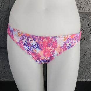 Colorful bikini bottom on a mannequin against a gray concrete wall.