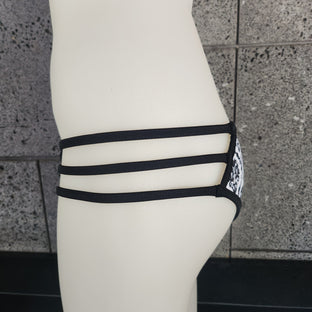 Pink and orange patterned bikini bottom on a mannequin against a dark background