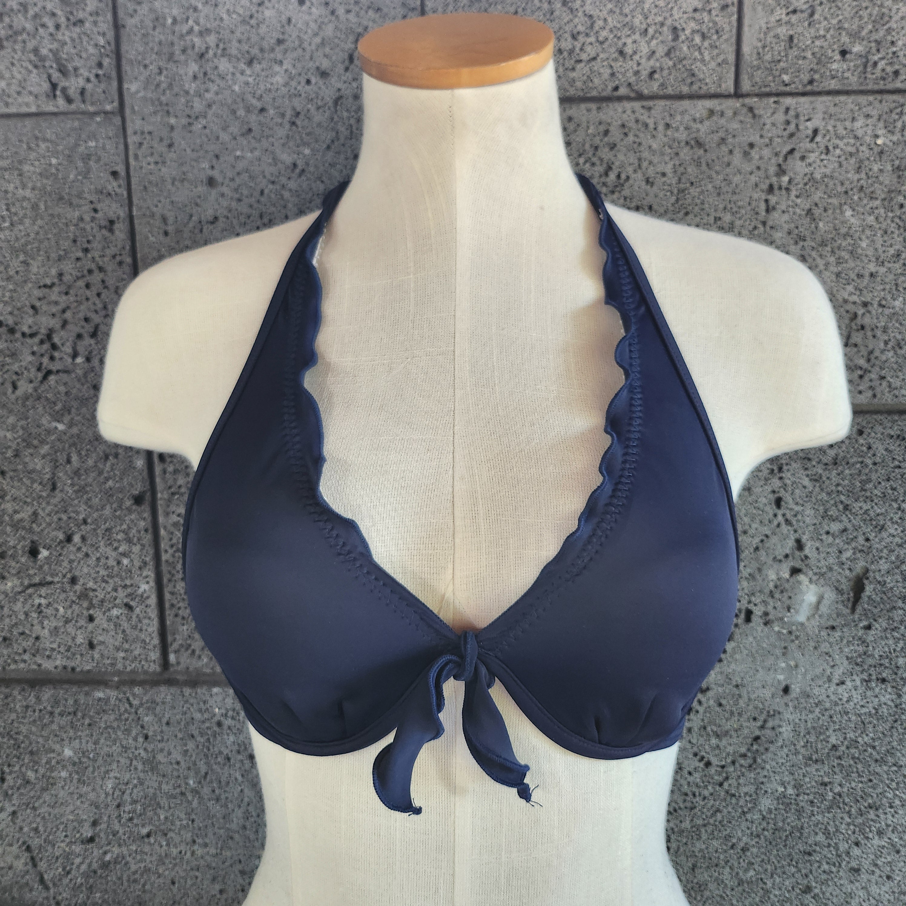 Navy blue bikini top on a mannequin against a gray tiled floor.