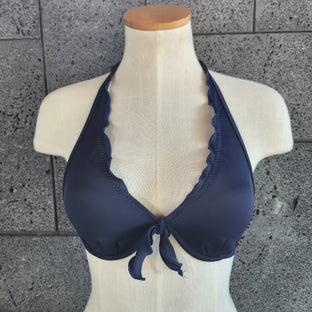 Navy blue bikini top on a mannequin against a gray tiled floor.