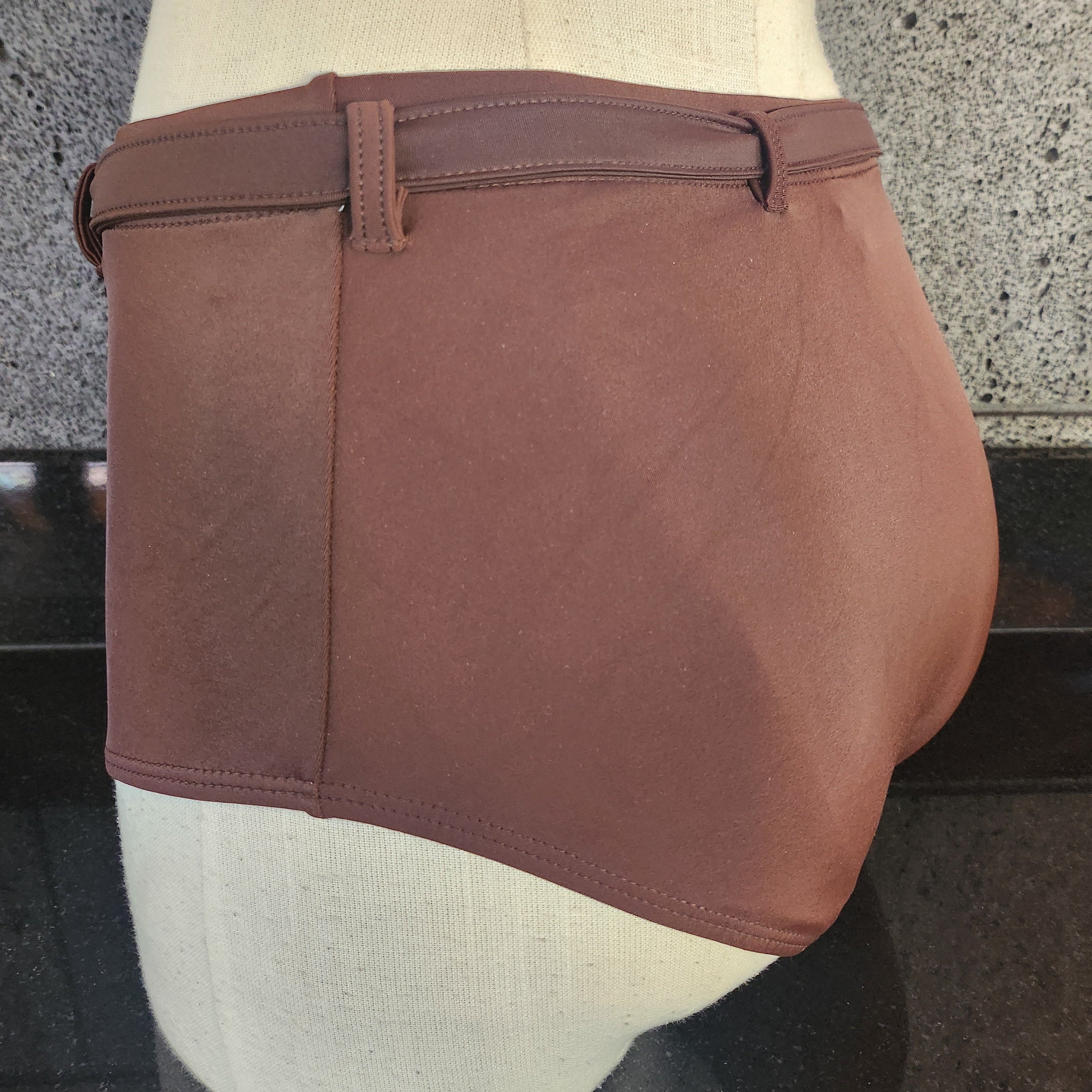 A high waisted brown bikini with a removable clasp belt, worn by a model.