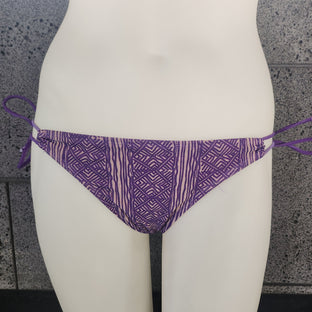 Purple patterned bikini top on a mannequin against a gray background