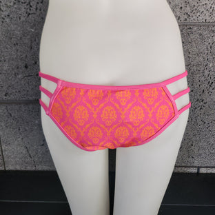Pink and orange patterned bikini bottom on a mannequin against a dark background