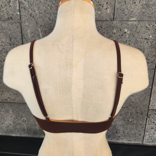 Blue bikini top on a mannequin against a tiled wall background