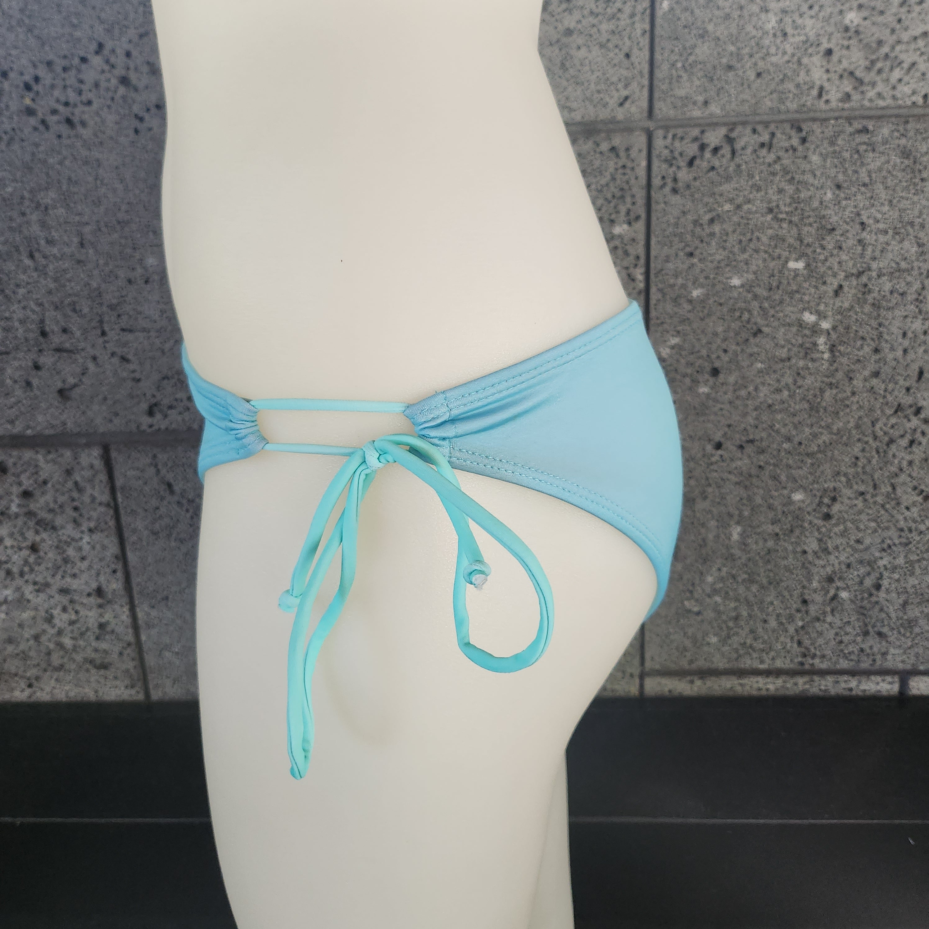 Blue bikini bottom on a mannequin against a white background