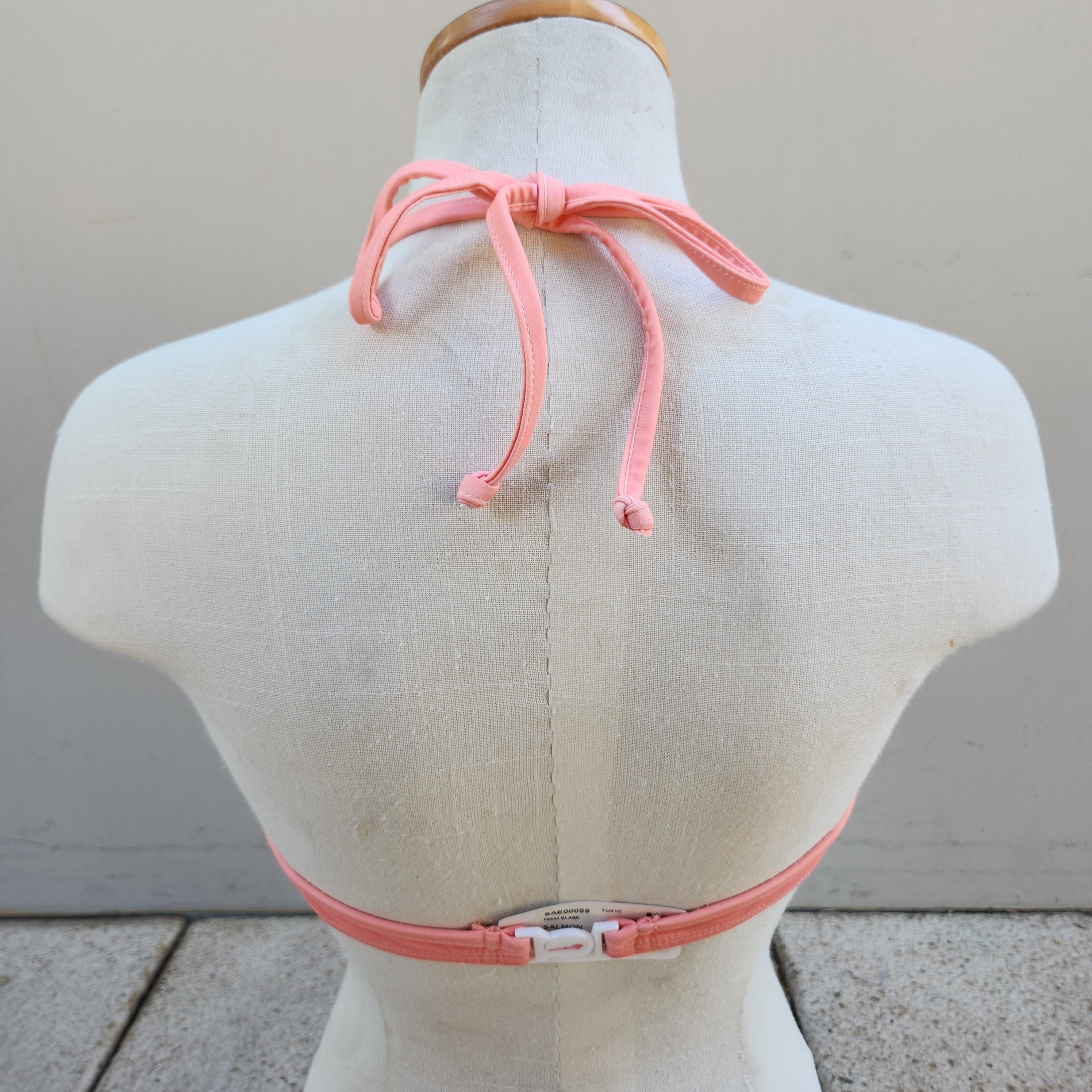 Navy blue bikini top on a mannequin against a gray tiled floor.
