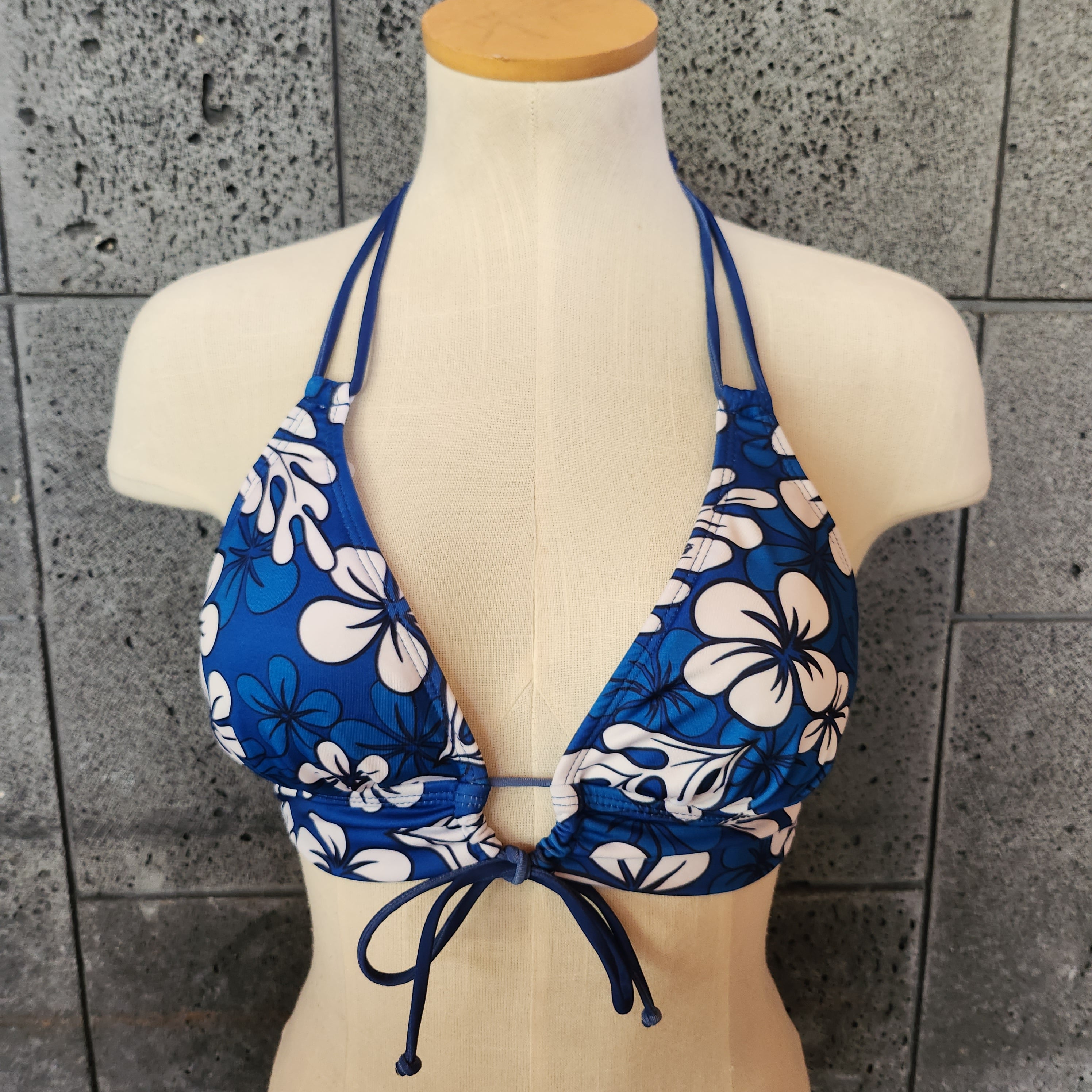 A woman wearing a blue floral bikini top with a keyhole front and banded chest.