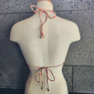 Colorful patterned bikini on a mannequin against a gray tiled floor background