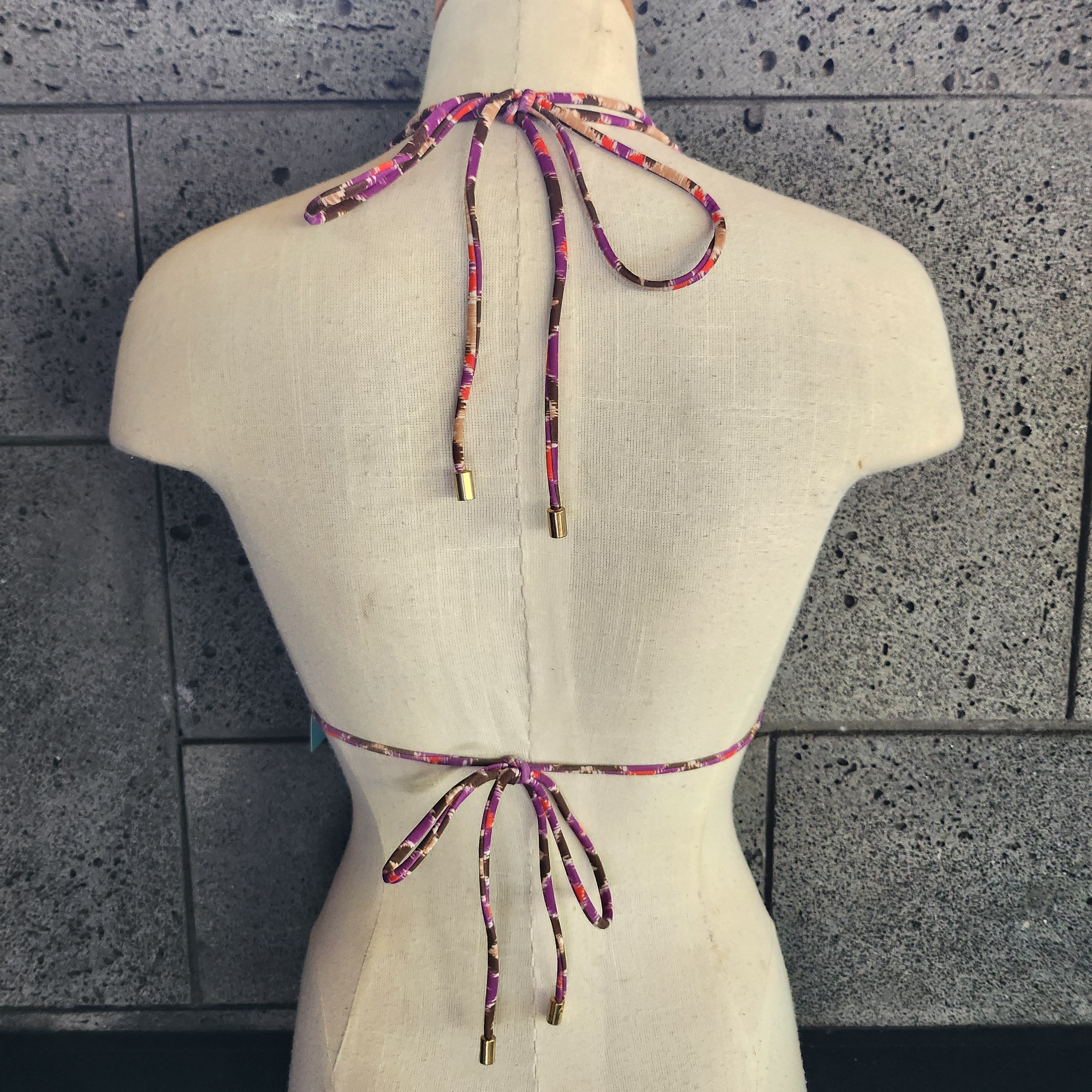 Colorful patterned bikini top on a mannequin with a white background.