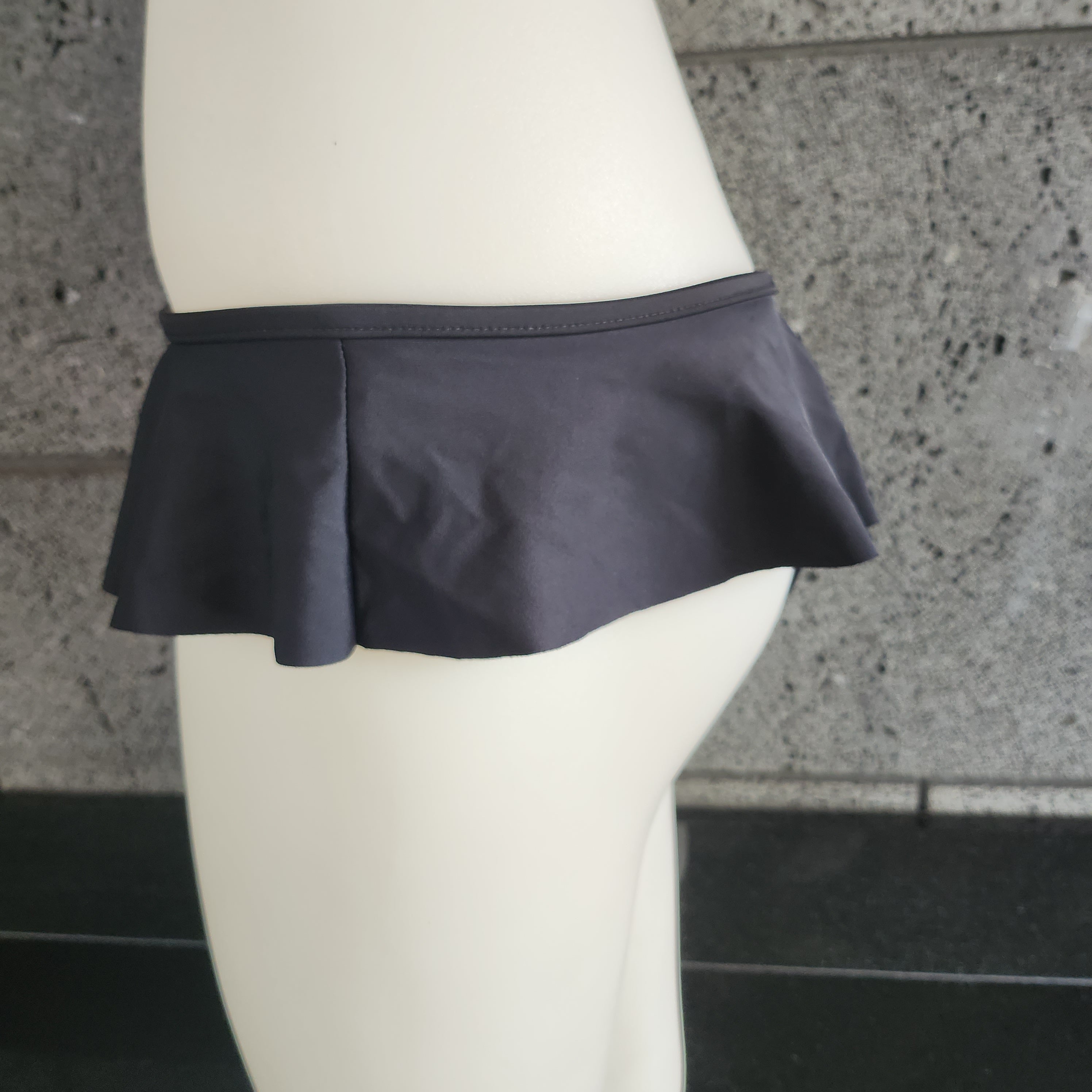 A pair of orange red ruffled skirted bottoms displayed on a mannequin.