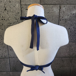 A woman wearing a blue and white floral high halter crop top with a coordinating bottom, standing against a white background.
