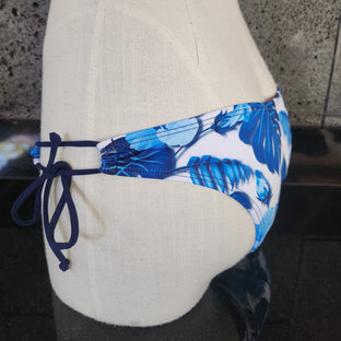 A swimsuit with a floral pattern, featuring a keyhole design and gathered fabric, primarily in blue and white colors. 
