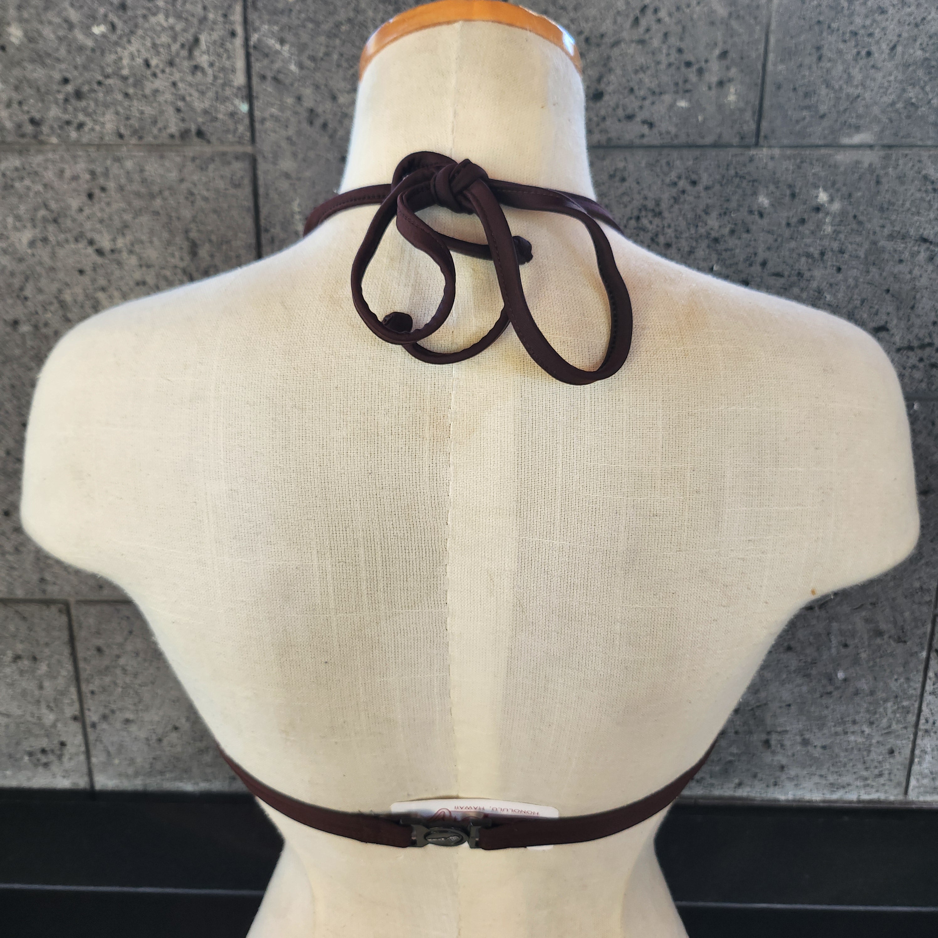 Navy blue bikini top on a mannequin against a gray tiled floor.