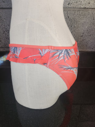 A mannequin bikini bottom wearing a navy blue bikini with a tropical floating palm print on top and double sided ruffles.