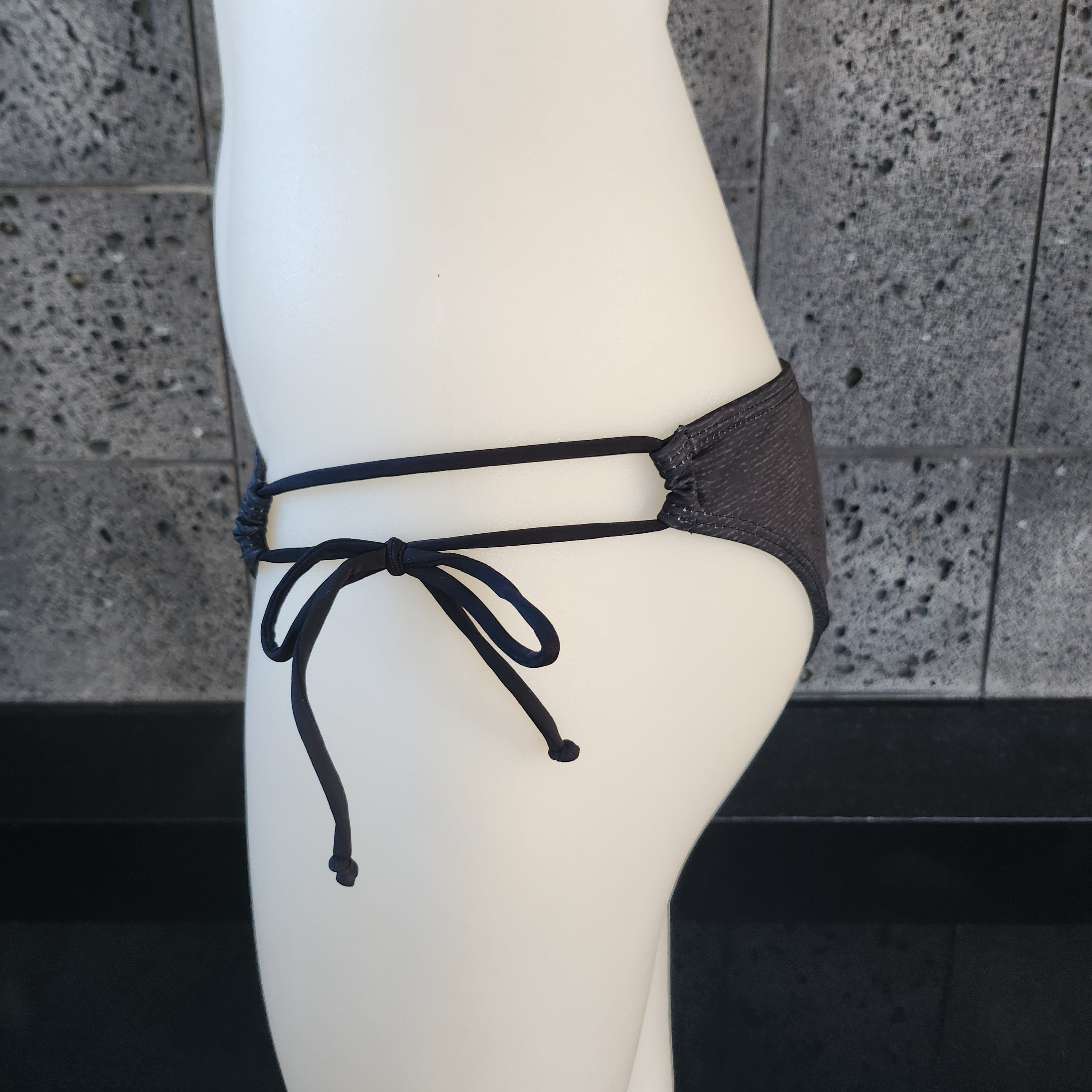 Purple patterned bikini top on a mannequin against a gray background