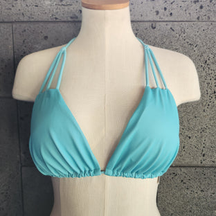 Turquoise bikini on a mannequin against a gray concrete background