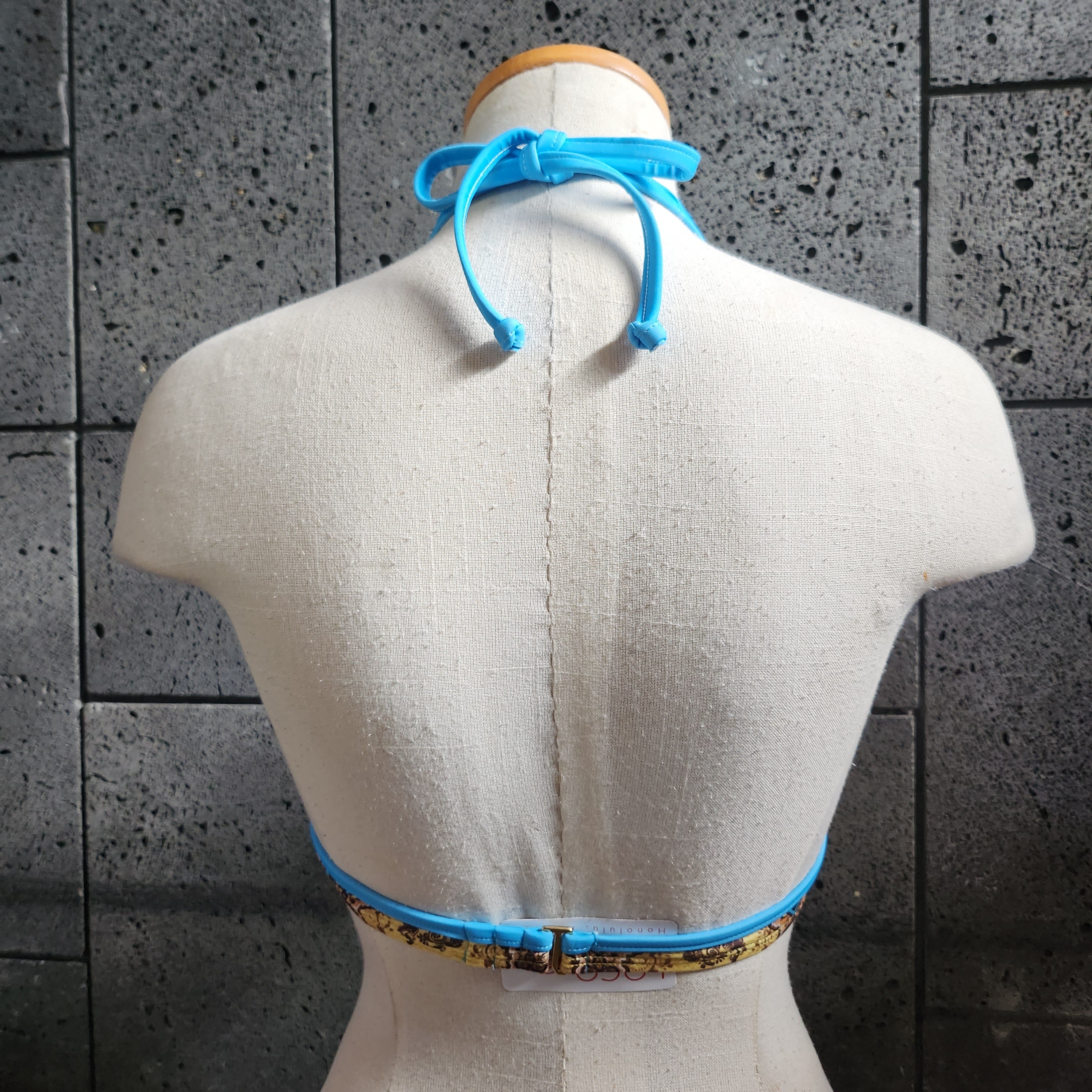 A woman wearing a turquoise and multicolor floral underwire bikini top with a bow front and back hook closure.