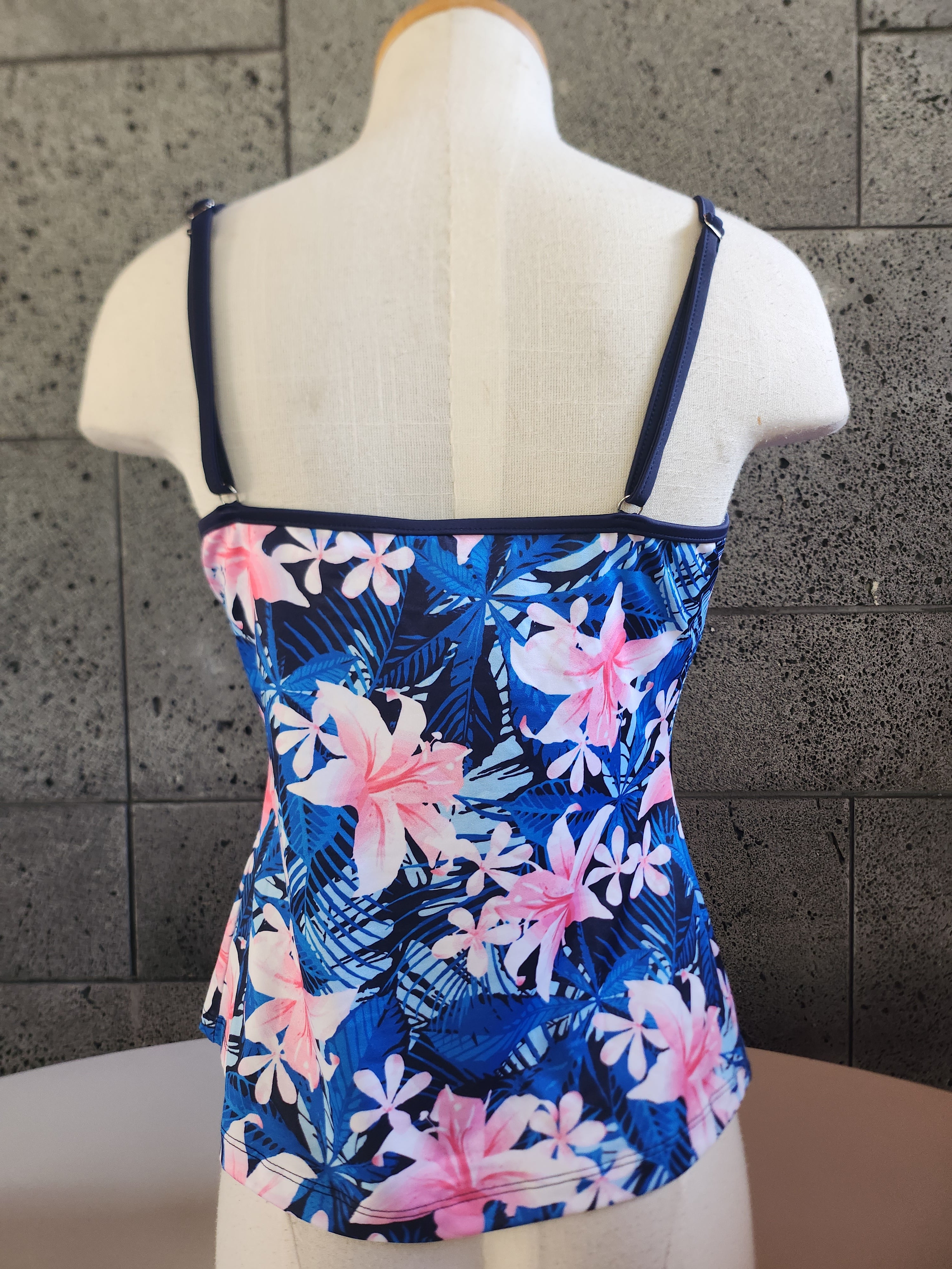 A woman wearing a blue and pink floral Casablanca Cami Tankini top with adjustable spaghetti straps.